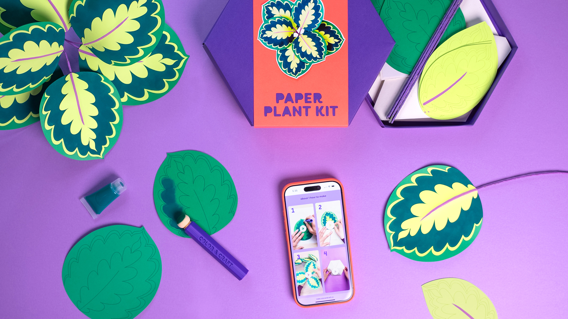 Paper plant kit with colorful paper leaves and crafting supplies on a purple background